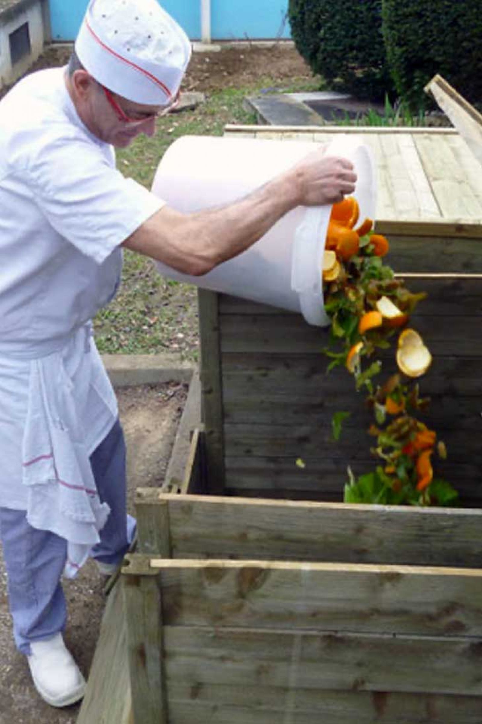 chef cuisinier jeté les bio-déchets, épluchures de fruits et légumes dans le composteur